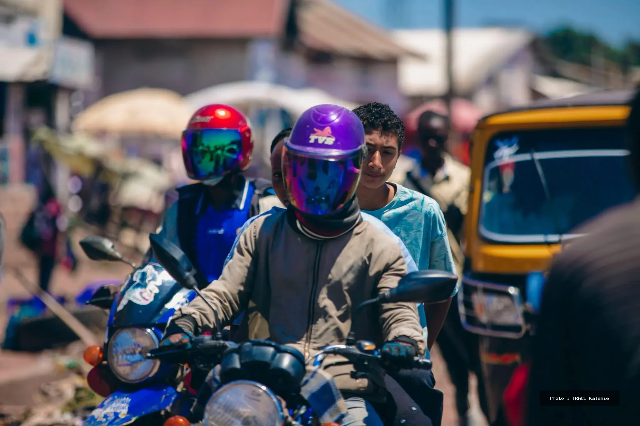 Motos-taxis et bajajs circulant dans une rue animée de Kalemie illustrant les défis de mobilité et les embouteillages dans la ville.